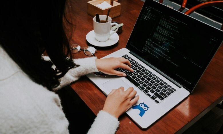 a woman using a laptop computer on a wooden table