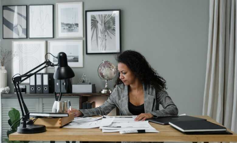 Businesswoman evaluates documents at a modern desk in a stylish office setting.