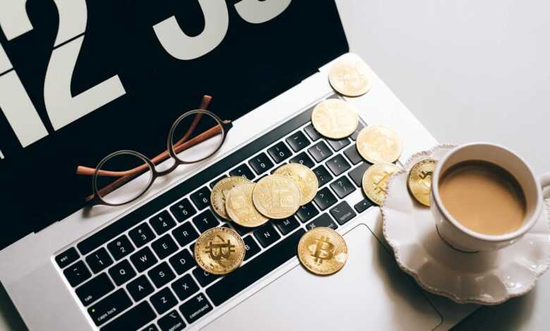 Laptop keyboard covered with Bitcoin coins and a coffee cup nearby, symbolizing cryptocurrency and work balance.