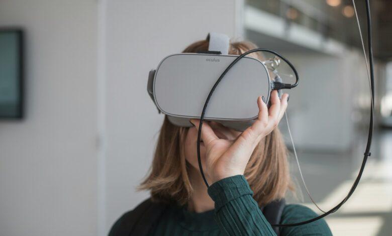 woman in black sweater holding white and black vr goggles