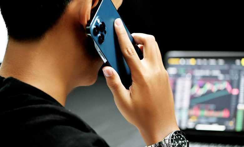 man in black long sleeve shirt holding blue smartphone