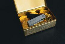 a swiss army knife sitting in a box of gold coins